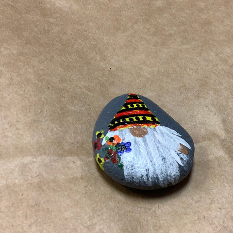 Small Gnome rock with orange  hat holding flowers.