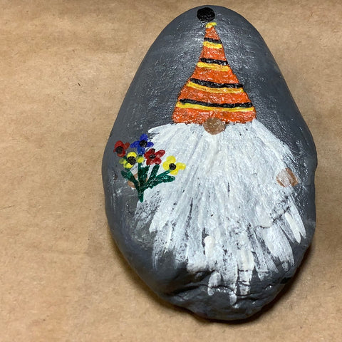 Gnome rock with orange striped hat holding flowers.