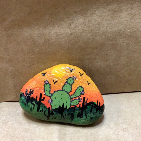 Cactus with orange sun background.  Hand painted on Rock by Cecelia.