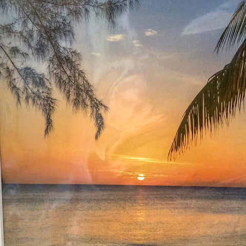 Sunset with sailboat in distance on ocean.