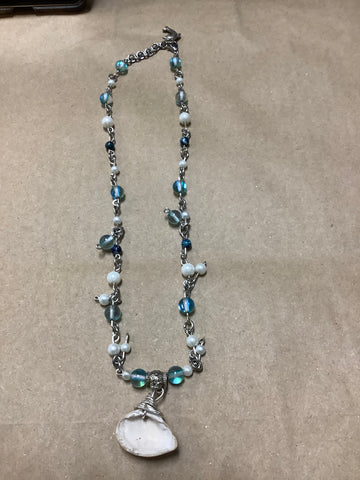 Gemstone Necklace with Blue and White and chain between with shell hanging down as focal point and dolphin by closure. By local artist Rowdeisha