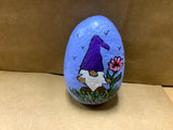 Hand Painted Rock of Gnome by a flowers standing in grass by local artist Cecelia.